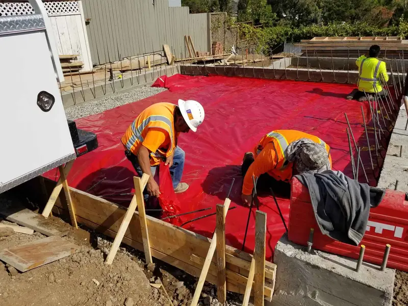 Crew installing the vapor barrier before the slab